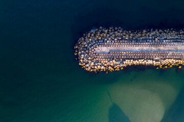 Obraz premium zenithal aerial view of a wave pier in a calm sea.