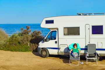 Woman enjoy sunlight, sitting on chair at caravan