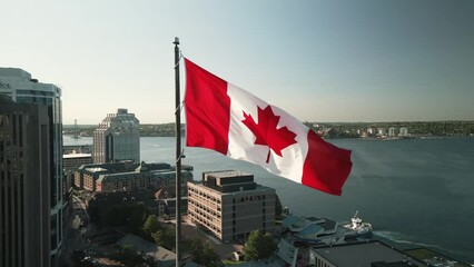 Aerial View of the Canadian Flag Waving in the Wind in the Center of the Modern City of Halifax, Canada. Drone Shot at the Waterfront and Skyscrapers with the Canada Flag in the Center.