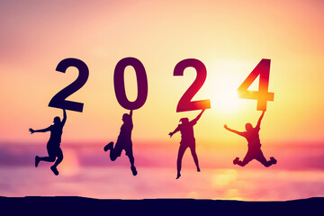 Silhouette friends jumping and holding number 2024 on sunset sky abstract background at tropical...