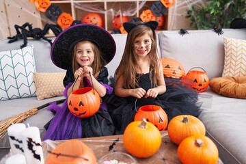 Fototapeta premium Adorable girls having halloween party holding pumpkin basket at home