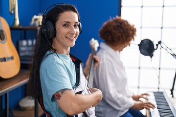 Obraz premium Two women musicians playing piano keyboard and electrical guitar at music studio