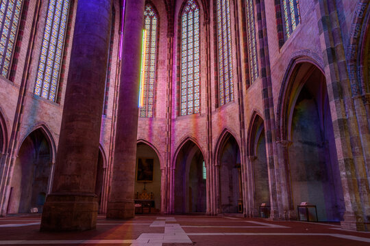 The nave of the church of the Jacobins, a 13th century church, lit up at night, with tall pillars with coloured lights