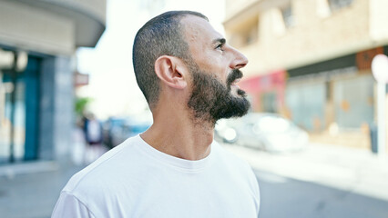 Young hispanic man looking to the side with serious expression at street