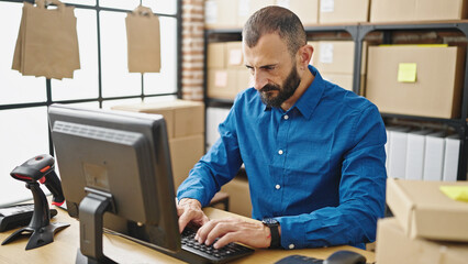 Young hispanic man ecommerce business worker using computer with serious face at office