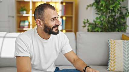 Young hispanic man smiling confident sitting on sofa speaking at home