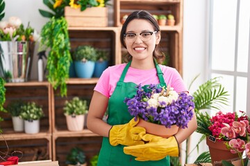 Hispanic young woman working at florist shop holding plant smiling with a happy and cool smile on face. showing teeth.