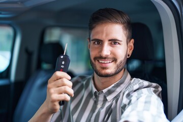 Young caucasian man smiling confident holding key of new car at street