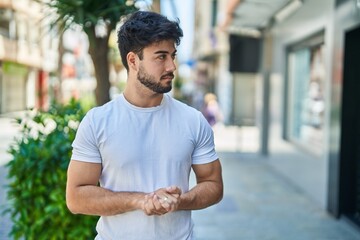 Young hispanic man with relaxed expression standing at street