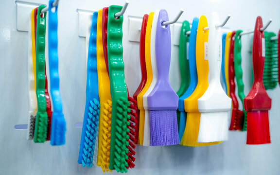 Brushes hang on shelf. Color coded hygiene glazing brushes and detail brushes for food processing and manufacturing. Cleaning tool for food safety in food and beverage industry. Durable cleaning brush