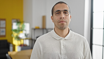 Fototapeta premium Young hispanic man business worker standing with relaxed expression at office