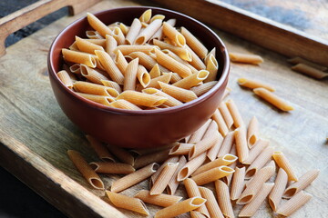 Whole grain penne pasta. Food background top view - obrazy, fototapety, plakaty