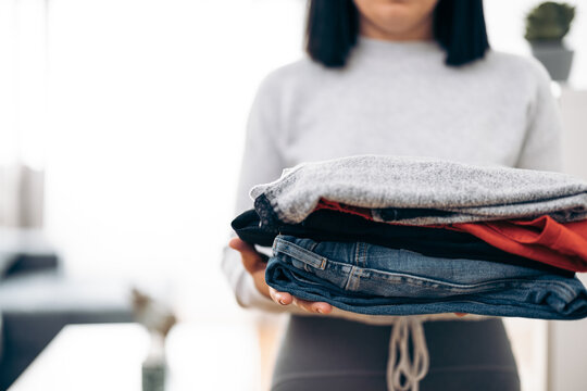 Unrecognizable woman carrying folded clothes