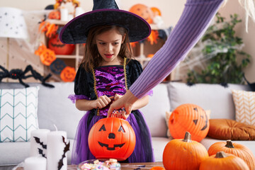 Adorable hispanic girl having halloween party receiving sweets at home