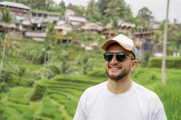 Naklejka na ściany i meble Young happy tourist enjoying the lovely view of the rice terrace in Bali, Indonesia. Man walking on rice terraces in Bali