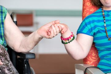 Close up of the hands of an 84 yo white woman and her 40 yo daughter with the Down Syndrome, Belgium