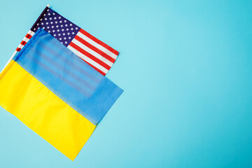 Ukrainian and American flags on blue background. Support Ukraine during war. Space mockup. Top view
