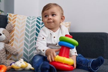 Adorable caucasian boy playing hoops game sitting on sofa at home