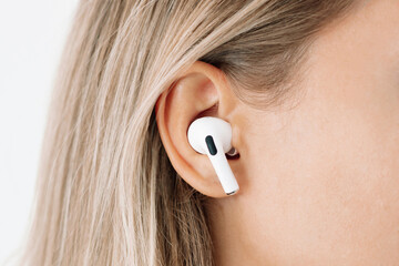 White wireless headphone for sports, running, cycling, walking in the ear of a young caucasian...