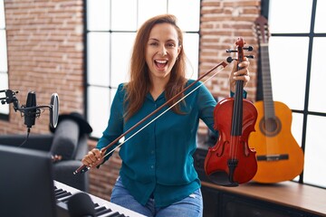 Brunette woman playing violin smiling and laughing hard out loud because funny crazy joke.