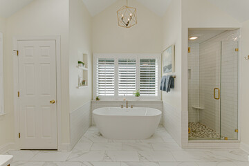 Luxurious Modern Primary Bathroom Interior With White Soaking Tub And Standing Glass Shower With...