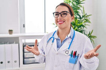 Young beautiful hispanic woman doctor smiling confident speaking at clinic