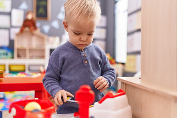Adorable caucasian boy standing with relaxed expression playing at kindergarten
