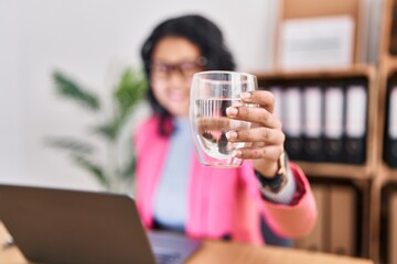 Young latin woman business worker using touchpad drinking water at office