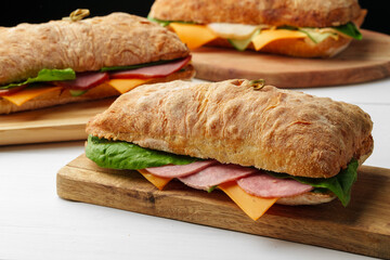 Chiabatta sandwich with ham and cheese on wooden board
