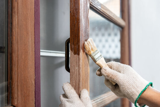 Worker use brush apply wood preserver after sandling the old surface of wooden window