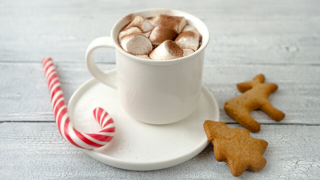 Hot chocolate with marshmallows in a white cup on a wooden surface.