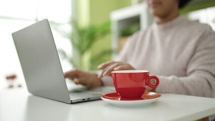 Young african american woman using laptop sitting on table at home