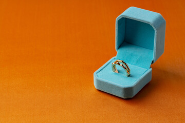 Golden ring in jewelry box on orange background