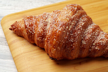 Freshly baked croissant with powdered sugar on wooden board