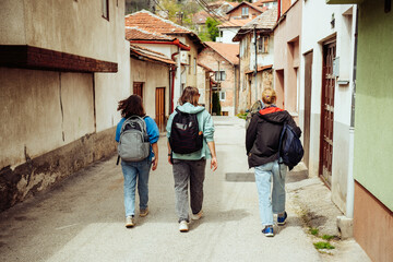 Three female friends of the traveler are walking through the narrow streets of the old European city. Hiking in historical places of the world