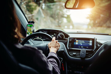 A woman holding the steering wheel tightly and driving a car. Traveling by car
