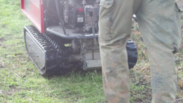 farmer using crawler mini dumper to transport heavy machinery in the vine yard on the hill.
