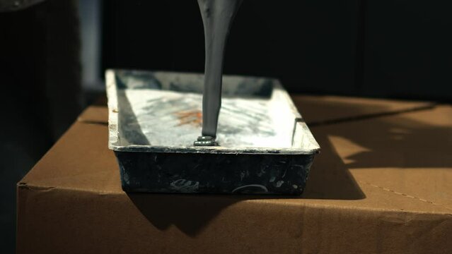Pouring gray paint into a roller tray