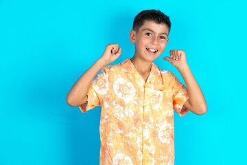 Hooray cool Little hispanic boy wearing hawaiian shirt  point back empty space hand fist