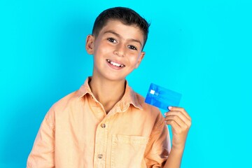 Close up photo of optimistic Little hispanic boy wearing orange shirt hold card