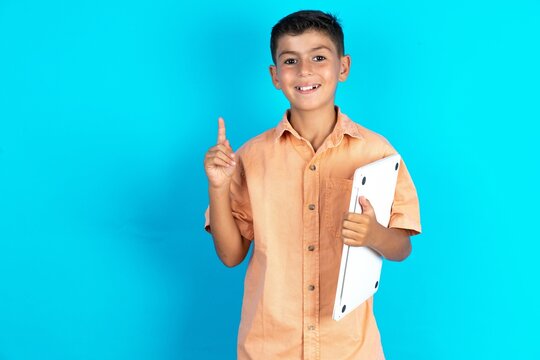 Little Hispanic Boy Wearing Orange Shirt Holding Laptop Showing Copy Empty Space Ad