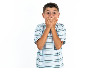 Vivacious Little hispanic kid boy wearing striped T-shirt , giggles joyfully, covers mouth, has...