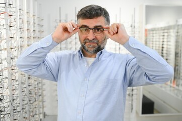 Fototapeta premium male customer choosing glasses in optics store