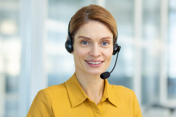 Portrait of successful smiling business woman with headset phone, mature experienced worker smiling...