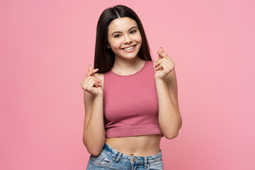 Smiling attractive teenage girl in pink top posing for picture isolated on pink background