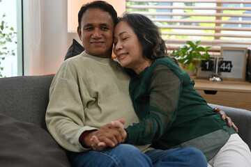 Fototapeta premium A heartwarming portrait of an elderly Asian couple embracing and holding hands with love at home.