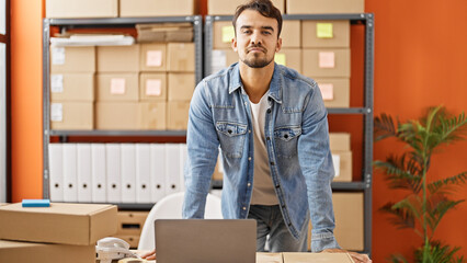 Young hispanic man ecommerce business worker standing by laptop at office