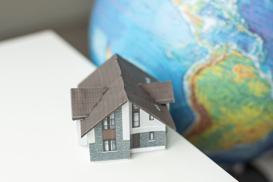 Model house with a world globe alongside in a conceptual image of saving the planet through eco-friendly construction and use of resources