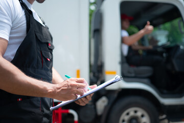 Closeup of delivery man check the list on the clipboard in front of the truck.