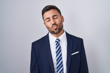 Handsome hispanic man wearing suit and tie looking at the camera blowing a kiss on air being lovely and sexy. love expression.